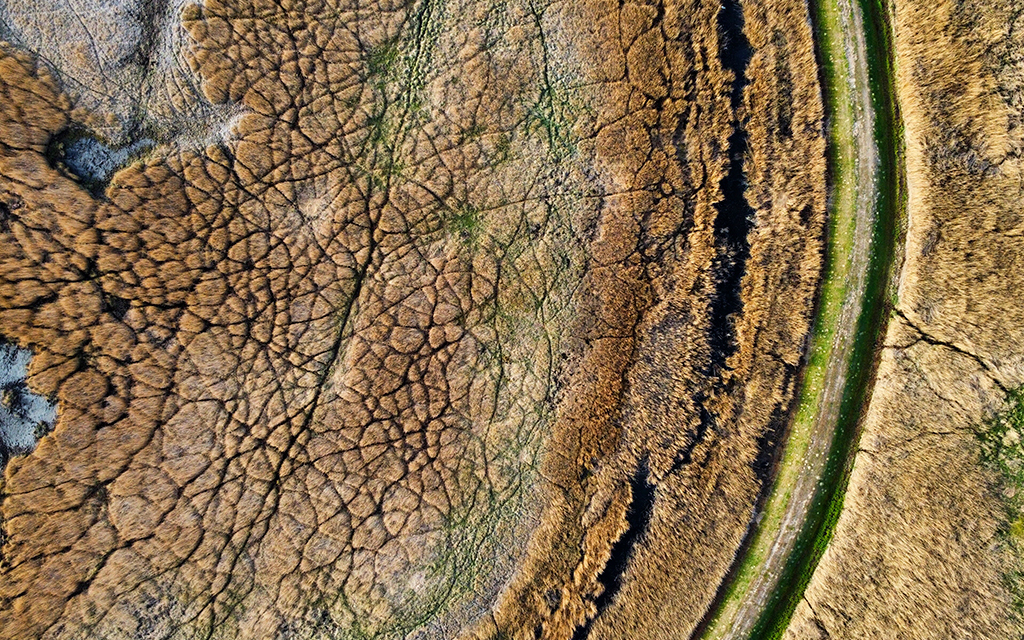 Drone view of cracked dry riverbed symbolizing environmental stress and land degradation