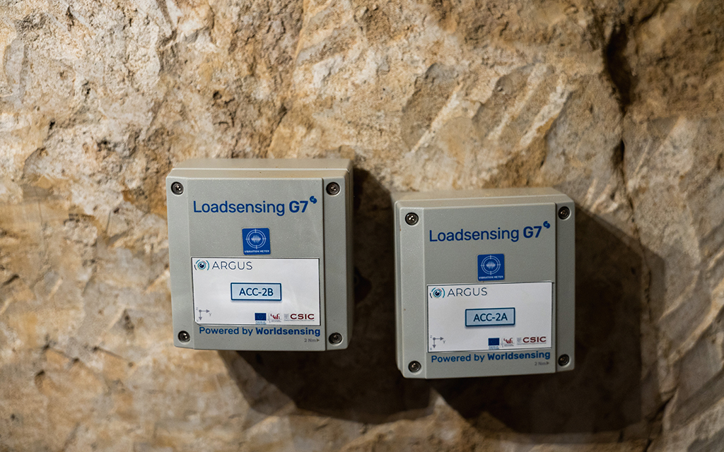 Two structural monitoring sensor units mounted on a stone wall in a heritage site